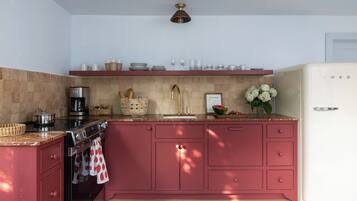 A kitchen with a red color scheme, a coffee maker, a sink, and a refrigerator.