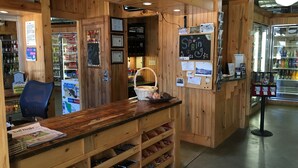 A wooden interior with a reception desk, shelves with snacks, a refrigerator with beverages, and a wall with various notices. - The Green Bridge Inn (Red Cliff)