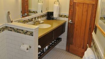 A bathroom with a wooden door, a white sink, a mirror, and a toilet.
