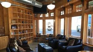 A cozy interior with leather sofas, a wooden bookshelf, and large windows overlooking a street. - The Green Bridge Inn (Red Cliff)