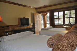 A hotel room with two beds, a television, a wooden door, and large windows.