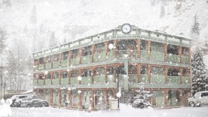 A multi-story building with a clock on the top, surrounded by snow. - The Green Bridge Inn (Red Cliff)