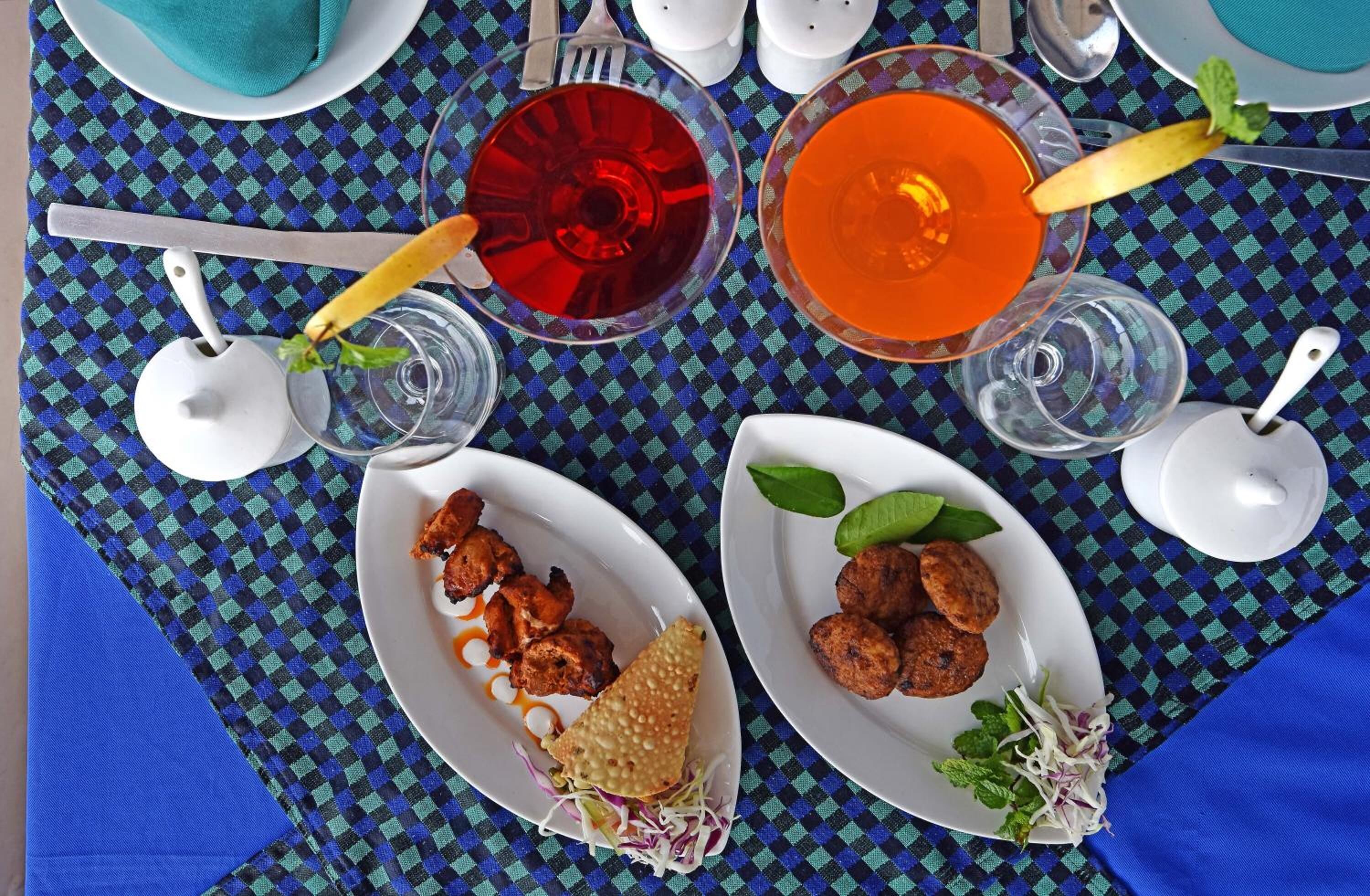A table set with plates of food, glasses of drinks, and cutlery.