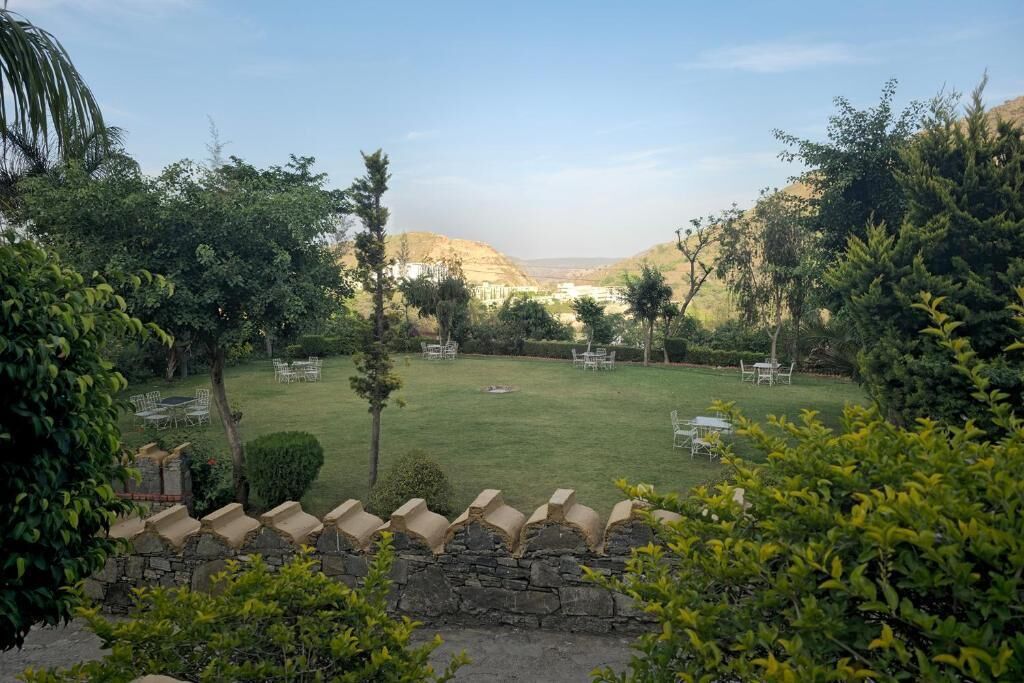 A well-maintained garden with a lawn, stone wall, and seating area.