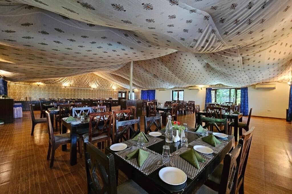Un vaste espace dédié à la salle à manger, avec de nombreuses tables et chaises, un plafond décoré et de grandes fenêtres laissant entrer la lumière naturelle.