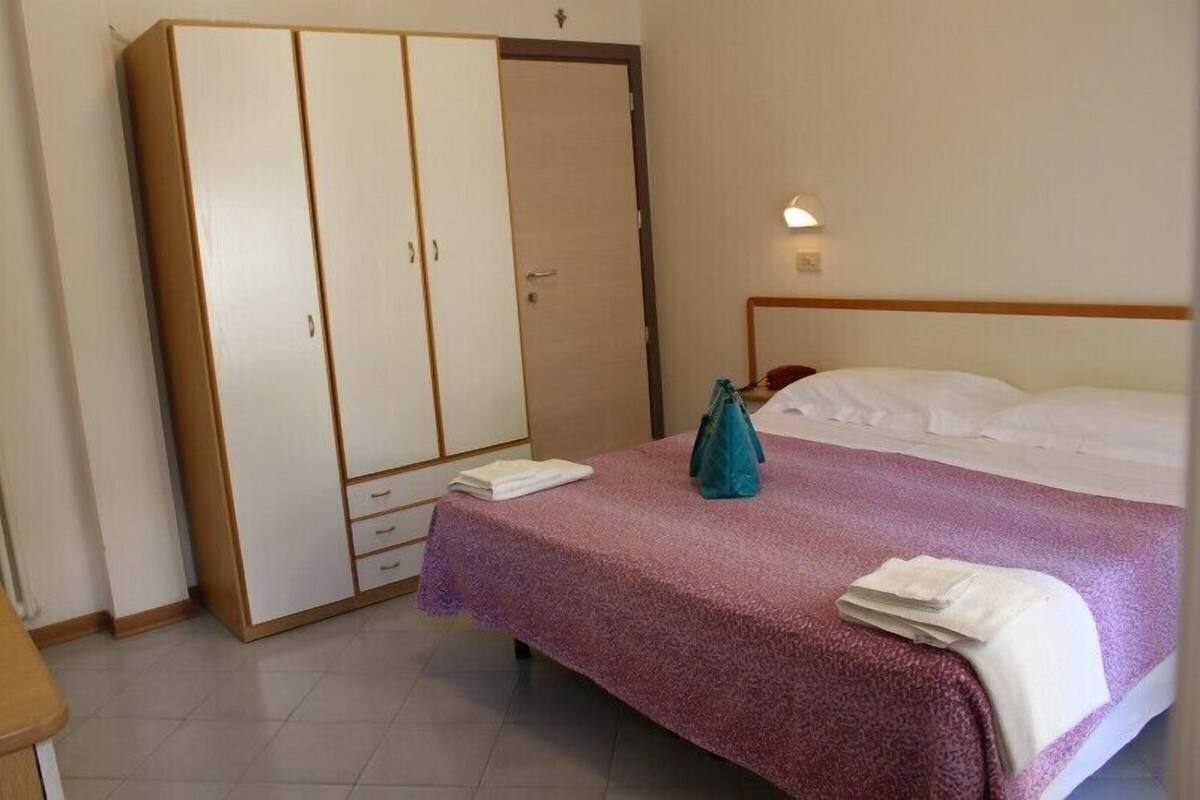 A bedroom with a bed, a wardrobe, and a nightstand.