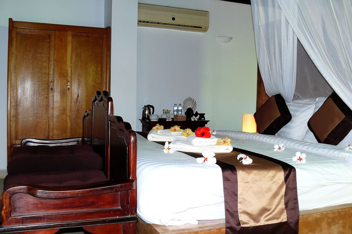 Una habitación de hotel con un armario de madera, una cama con dosel y una mesita de noche con artículos de aseo.