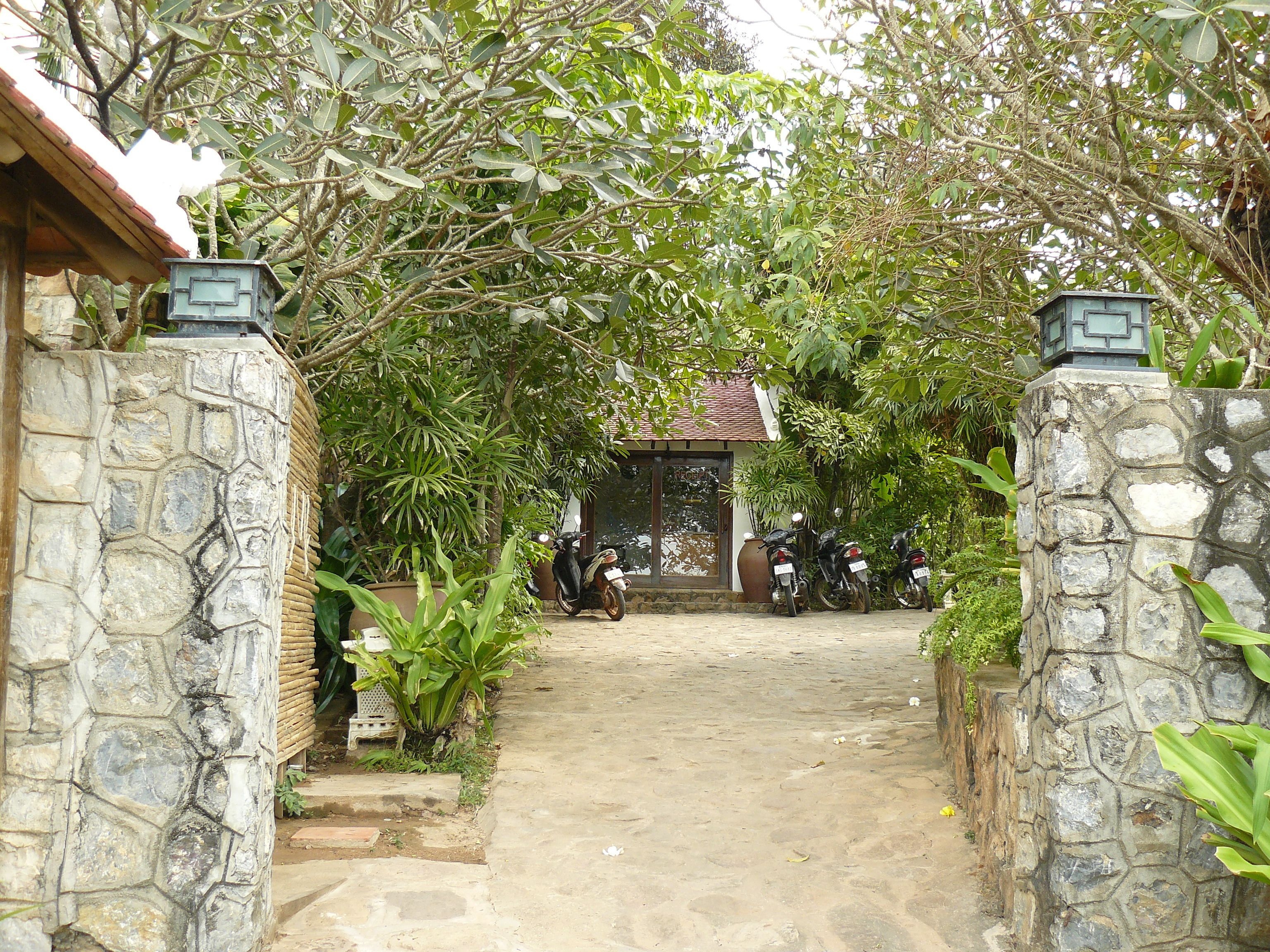 A stone-walled entrance with a paved path leading to a building.