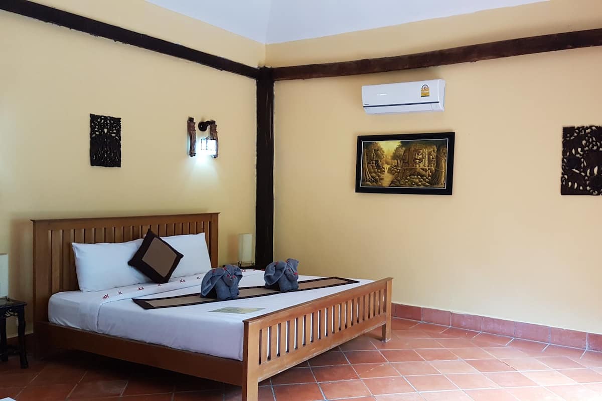 Una habitación con una cama de madera, aire acondicionado en la pared y decoración mural.