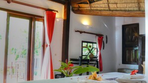 Una habitación con cama, ventana con cortinas rojas, una planta y una mesa con toallas.