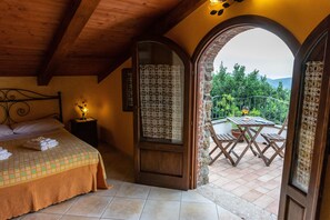 A bedroom with a bed, a nightstand, and a view of an outdoor patio with a table and chairs.