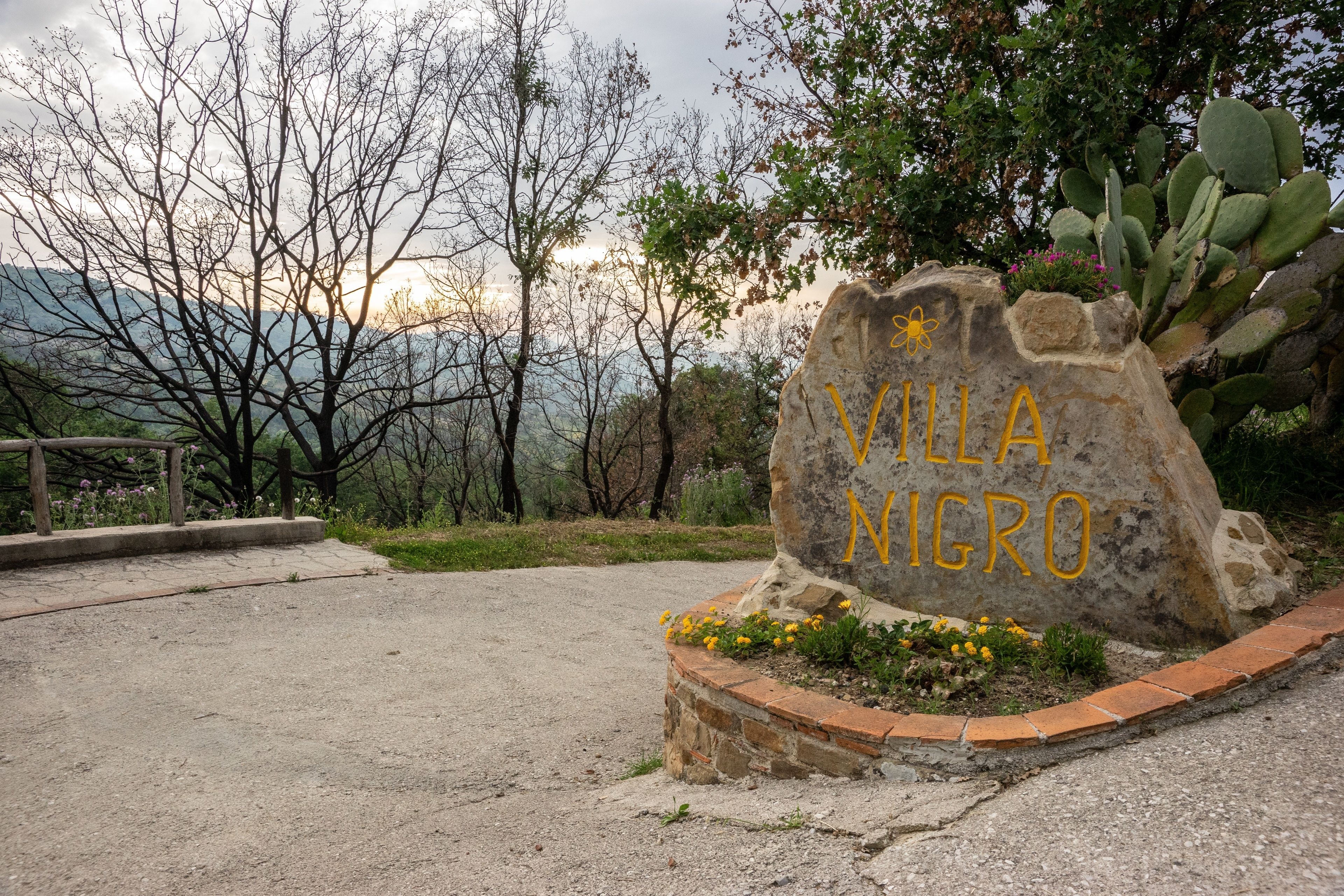A stone sign with "VILLA NIGRO" written in yellow.