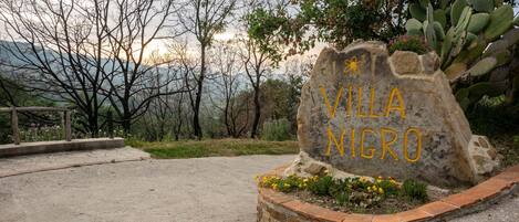 A stone sign with "VILLA NIGRO" written in yellow.