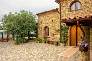 A stone building with a wooden door, a bench, and potted plants.