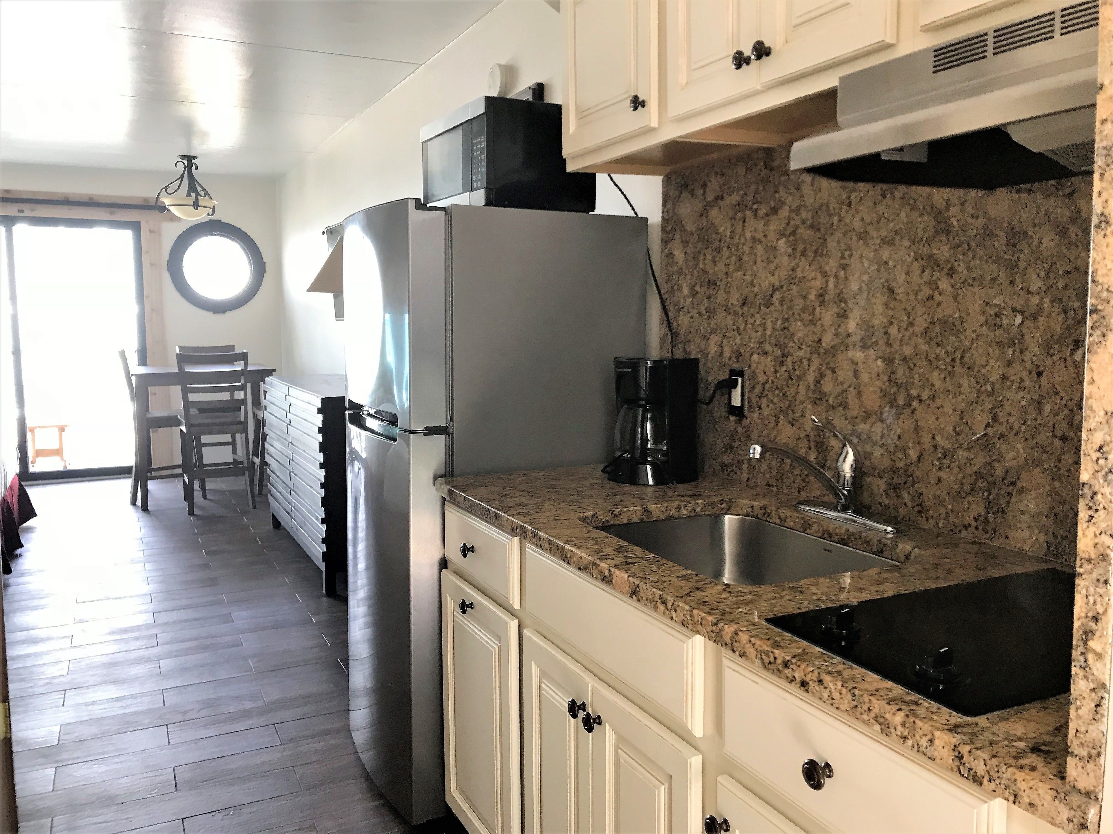 A kitchen with a granite countertop, stainless steel sink, and a refrigerator.