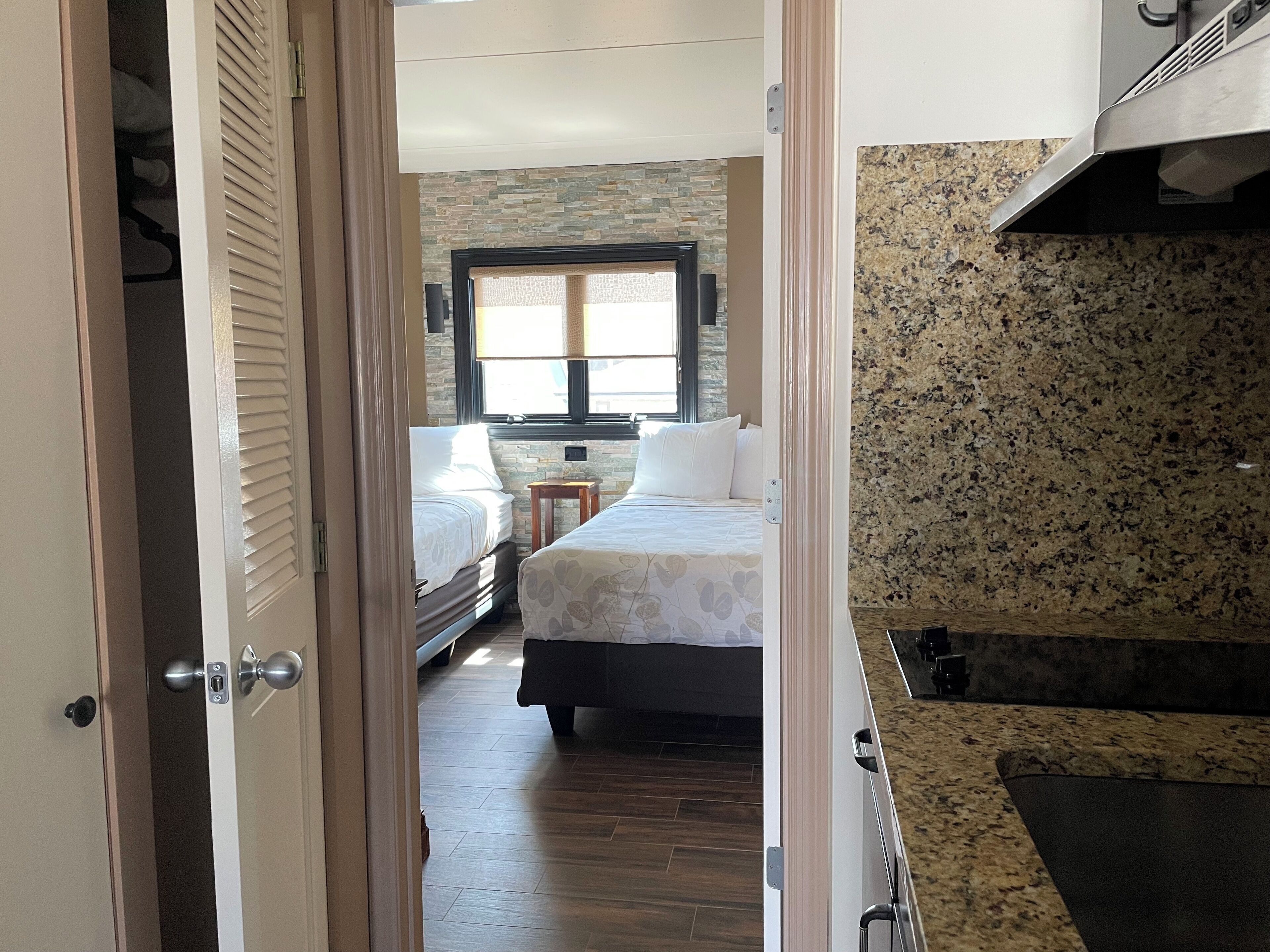 Una habitación de hotel con una cama, una mesita y una ventana.