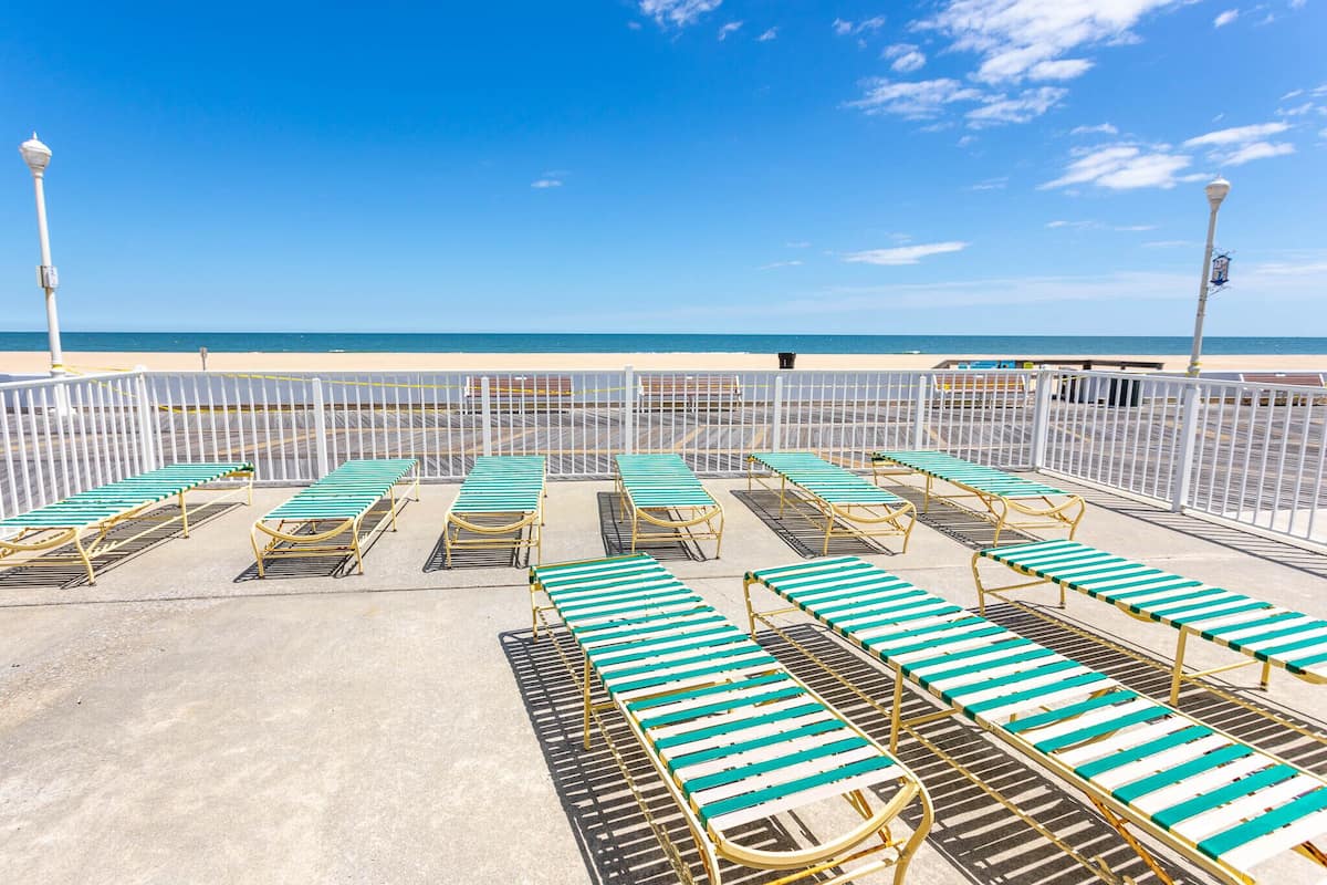 A beachside promenade with rows of sun loungers and a white fence.