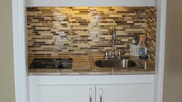 Una cocina con armarios blancos, un lavamanos de acero inoxidable y un salpicadero de mosaicos.