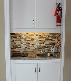 A kitchen with white cabinets, a stainless steel sink, and a mosaic backsplash.