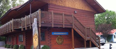 A wooden lodge with a balcony, a staircase, and a sign indicating it is a Sun Inn.