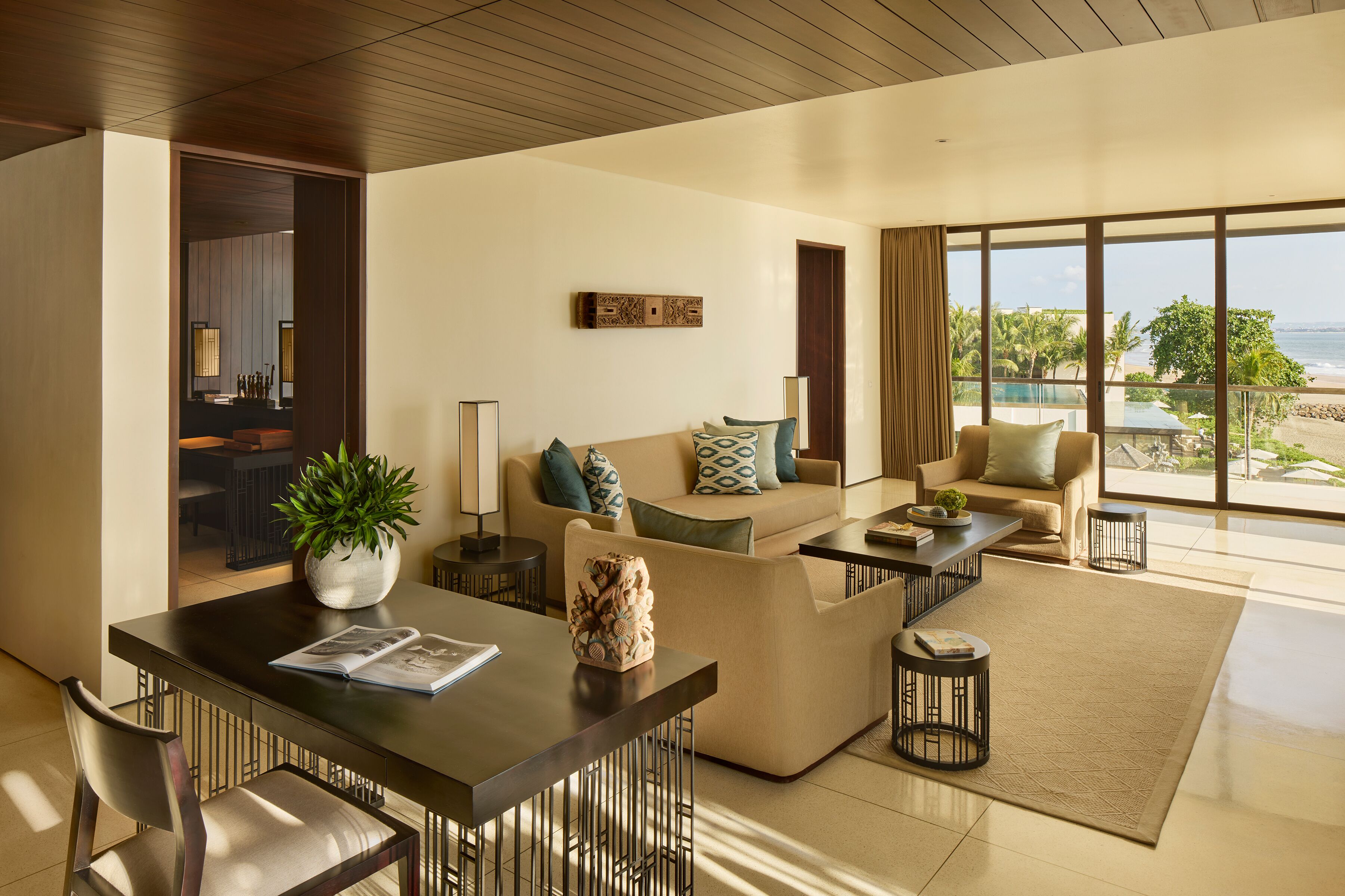 A modern living room with a dining area, large windows with a view of the beach, and a cozy seating arrangement.