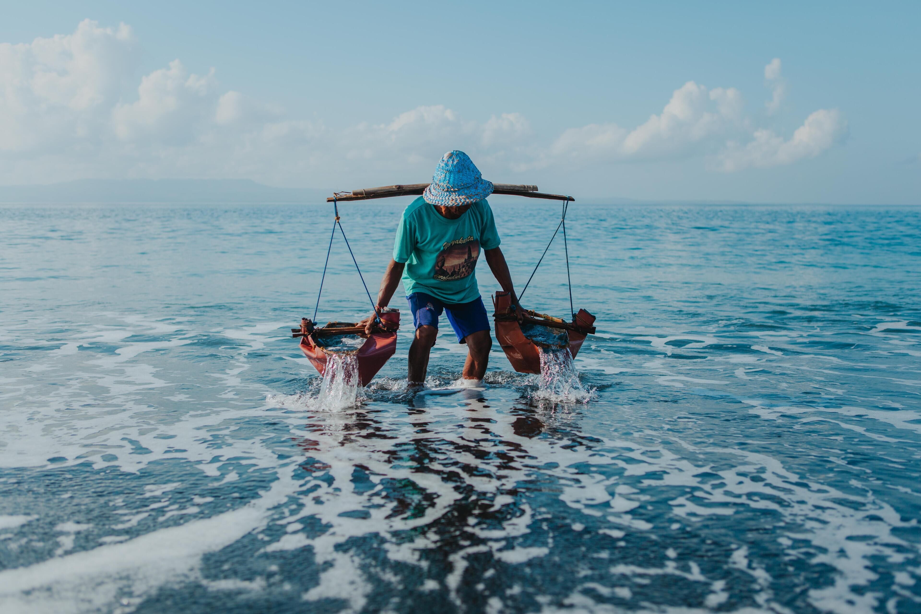 A person standing in a boat on a body of water.