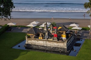 A beachfront property with a pool, umbrellas, and a traditional structure.