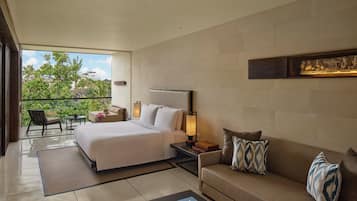 A modern hotel room with a large bed, a sofa, a coffee table, and a balcony with a view of greenery.