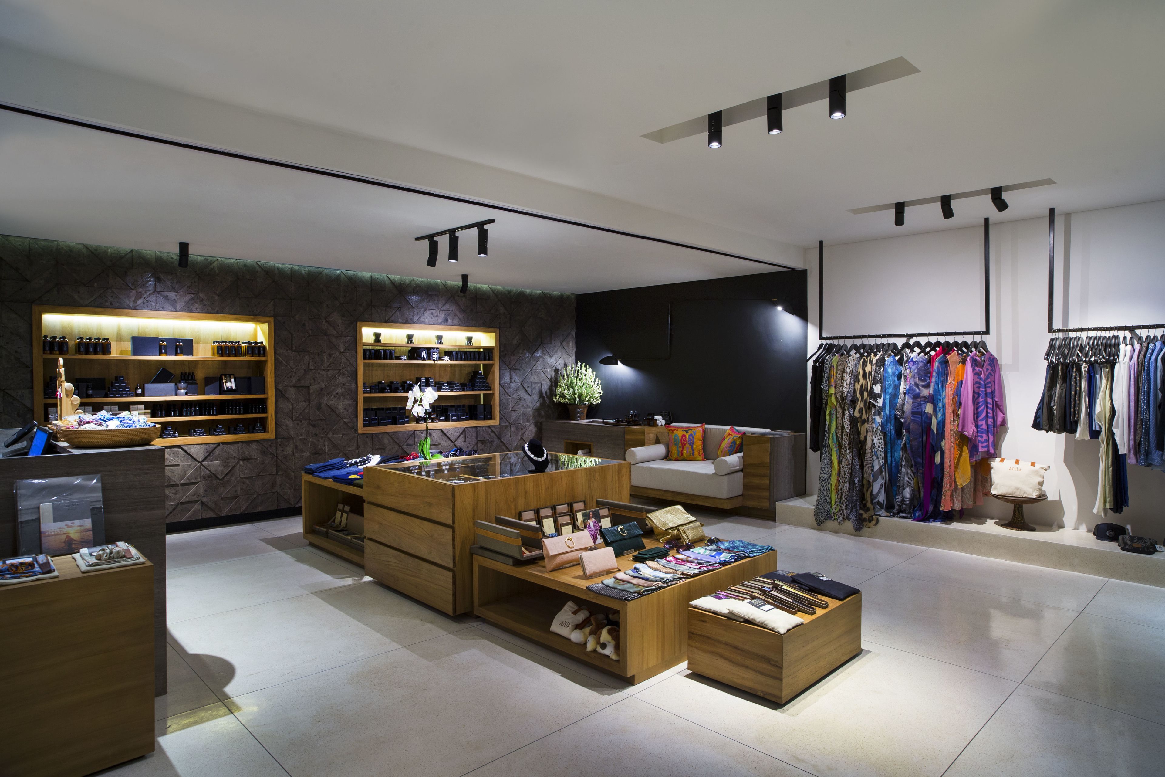 A modern retail store with wooden display units, a clothing rack, and a seating area.