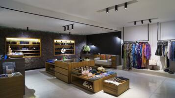 A modern retail store with wooden display units, a clothing rack, and a seating area.