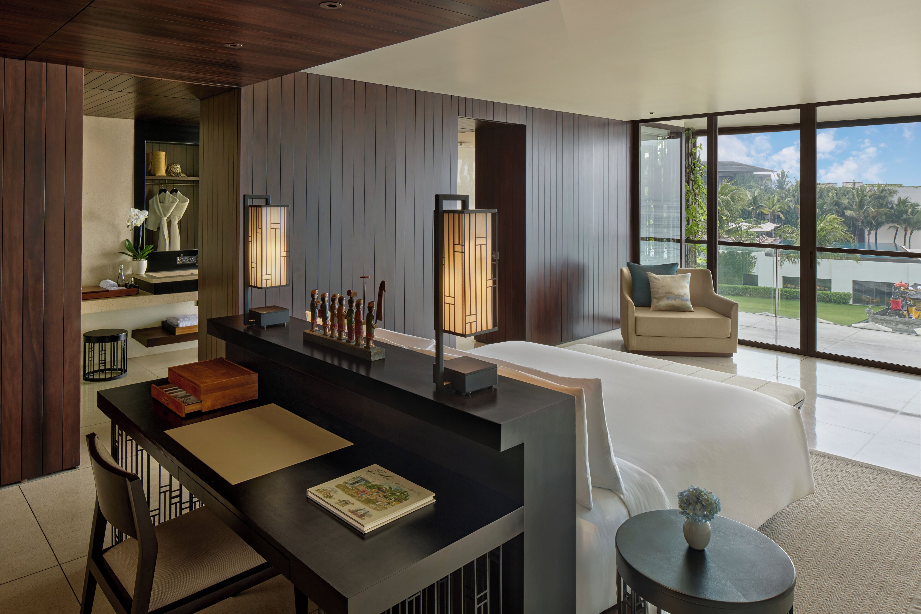 Una habitación de hotel moderna con un ventanal grande, un comedor con mesa y sillas, y un rincón de descanso acogedor con un sofá.