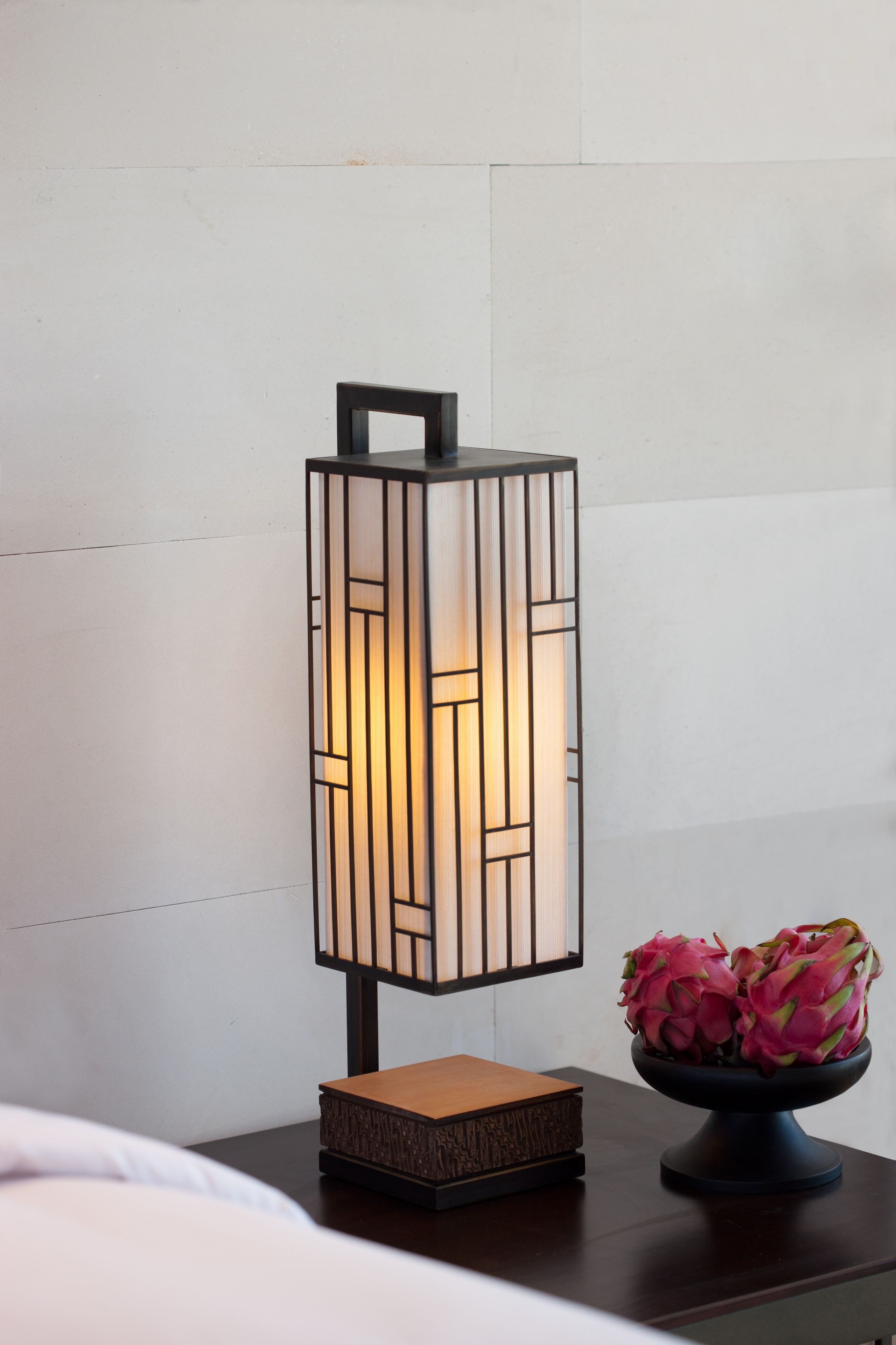 A bedside table with a decorative lantern and a bowl of flowers.