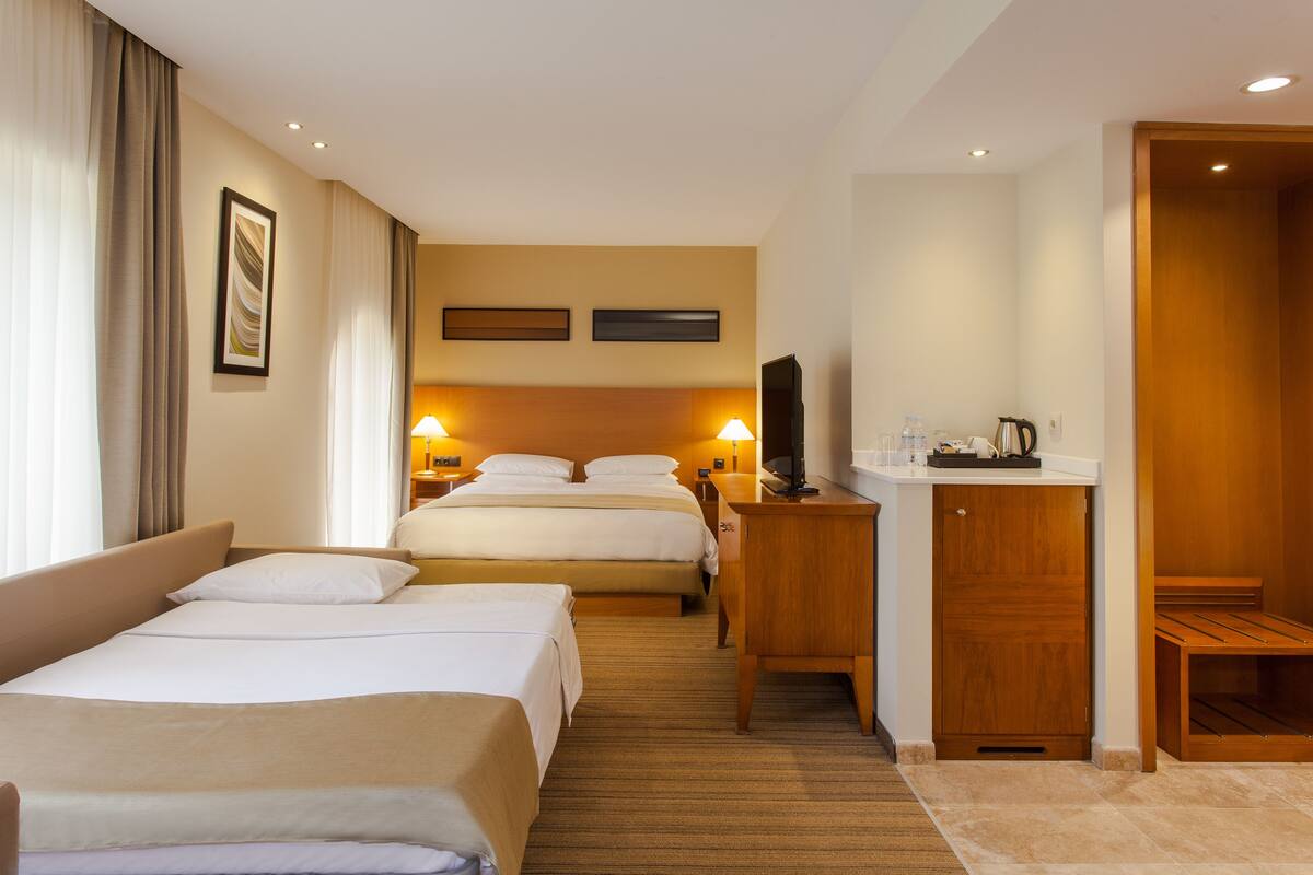 A hotel room with two beds, a desk, a television, and a wardrobe.
