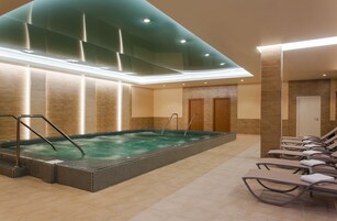 Un espace spa comprenant un jacuzzi, des chaises longues et un sol carrelé.
