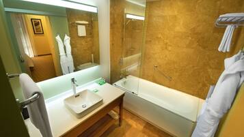 Un baño moderno con ducha separada por vidrio, un lavamanos blanco y un espejo grande.