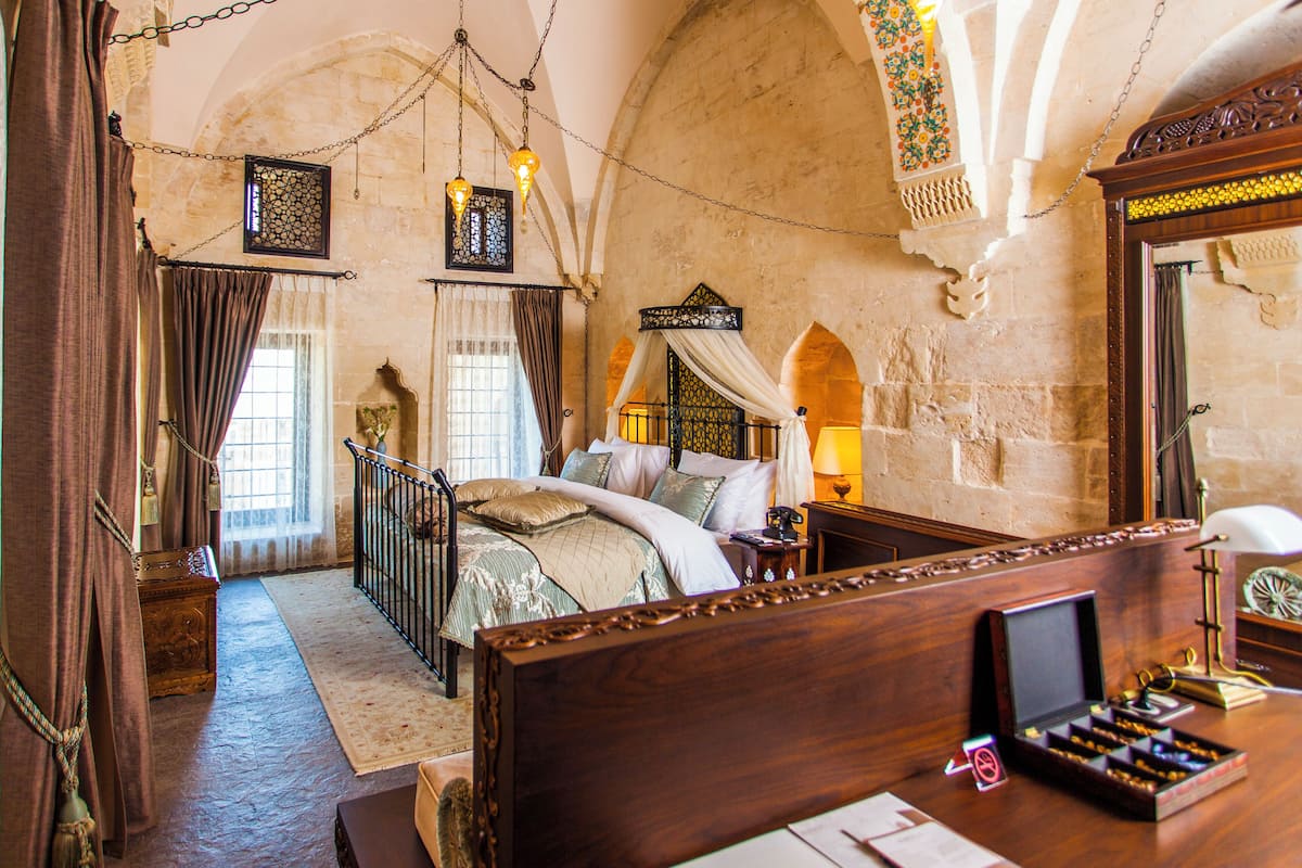 Quarto tradicional com cama, mesa de cabeceira e um espelho grande.