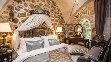 Un dormitorio con pared de piedra, cama con dosel y mesita de noche con lámpara.
