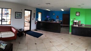 A living room with a red sofa, a coffee table, and a TV mounted on the wall. - Executive Inn (Groves)