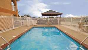 A rectangular pool with a wooden deck and a fenced area with lounge chairs. - Executive Inn (Groves)