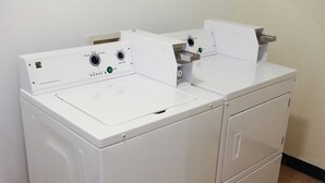 A front-loading white washer and dryer unit with control knobs and a start button. - Executive Inn (Groves)