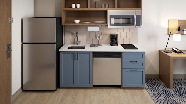 A compact kitchen with a built-in microwave, a coffee maker, and a refrigerator. - Executive Inn (Groves)