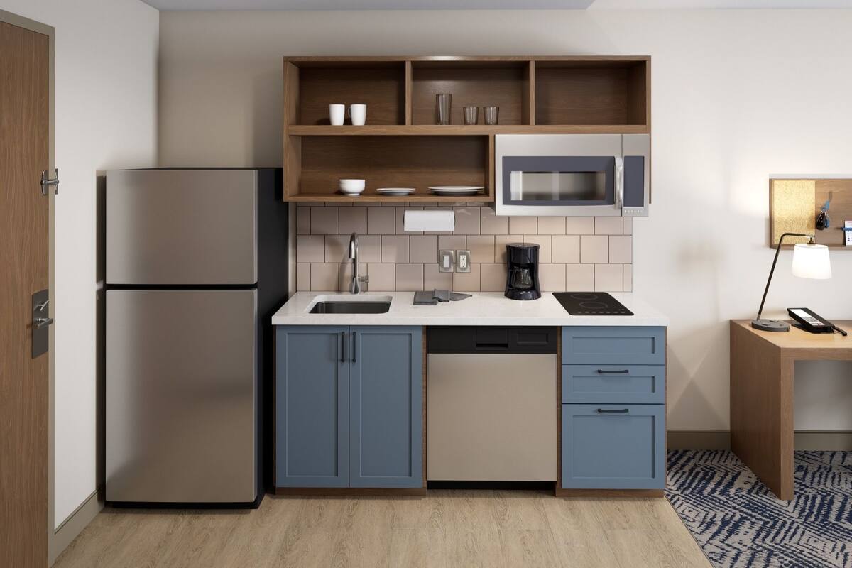 Una cocina compacta equipada con microondas, cafetera y refrigerador.