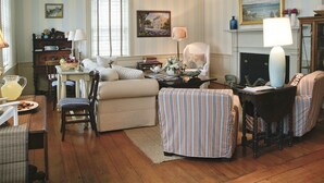 A cozy living room with striped wallpaper, a fireplace, and a dining area with a table and chairs. - Ships Inn (Nantucket)