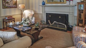 A living room with a fireplace, a sofa, a chair, a coffee table, and a lamp. - Ships Inn (Nantucket)