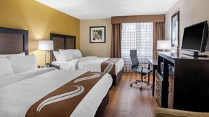 Une chambre d’hôtel avec deux lits, un bureau, une chaise, une télévision et une fenêtre avec des rideaux.