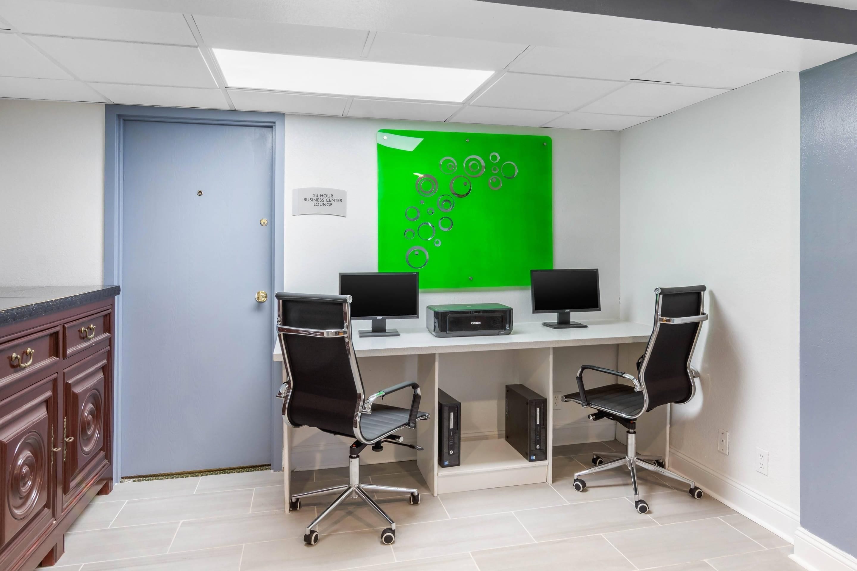 Ein rund um die Uhr geöffnete Business-Station mit zwei Computerarbeitsplätzen, Stühlen und einem Greenscreen.