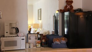 A kitchen area with a microwave, coffee maker, refrigerator, and a teddy bear on the counter. - Black Bear Inn (Dubois)