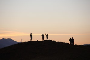 Un grupo de personas de pie en una colina con un atardecer de fondo.