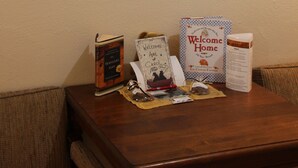 A framed wildlife photograph, a book, a welcome home sign, and a tissue box on a wooden table. - Black Bear Inn (Dubois)