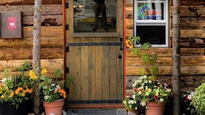 A wooden building with a sign reading "FLY SHOP & GUIDE SERVICE" and a logo for "WIND RIVER FLYFITTER". - Black Bear Inn (Dubois)